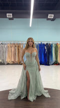 Front full-length view of woman wearing sage green strapless corset evening gown with high leg slit and train