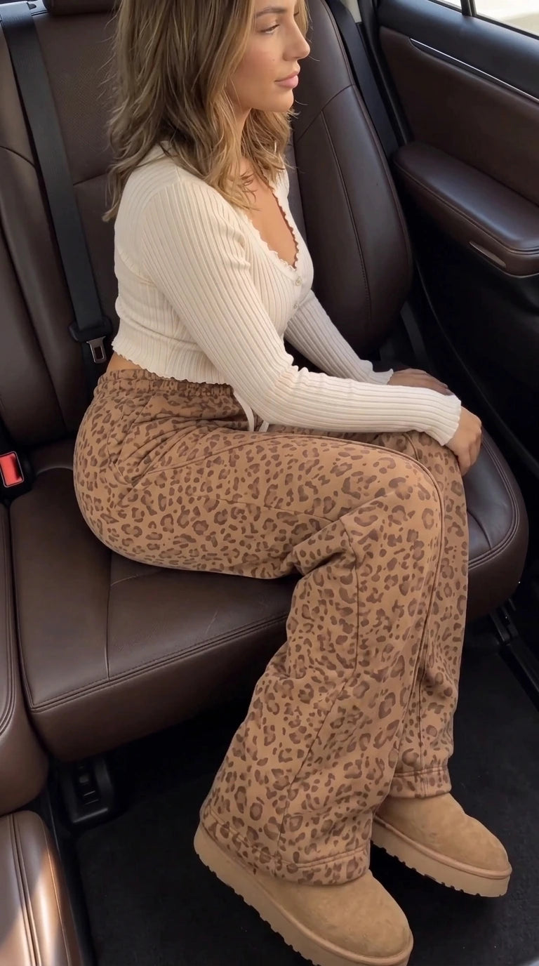 Side seated view of model in cream ribbed top and high-waisted camel leopard wide-leg pants