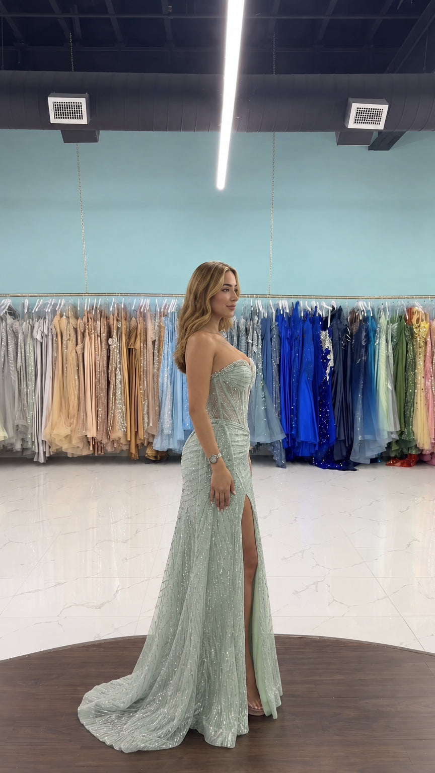 Side profile view of woman modeling sage green strapless sequin gown with side slit