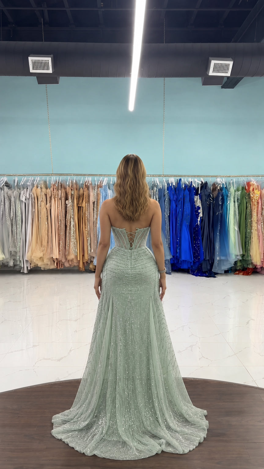Back full-length view of woman showing the back corset and flowing train of sage green evening gown