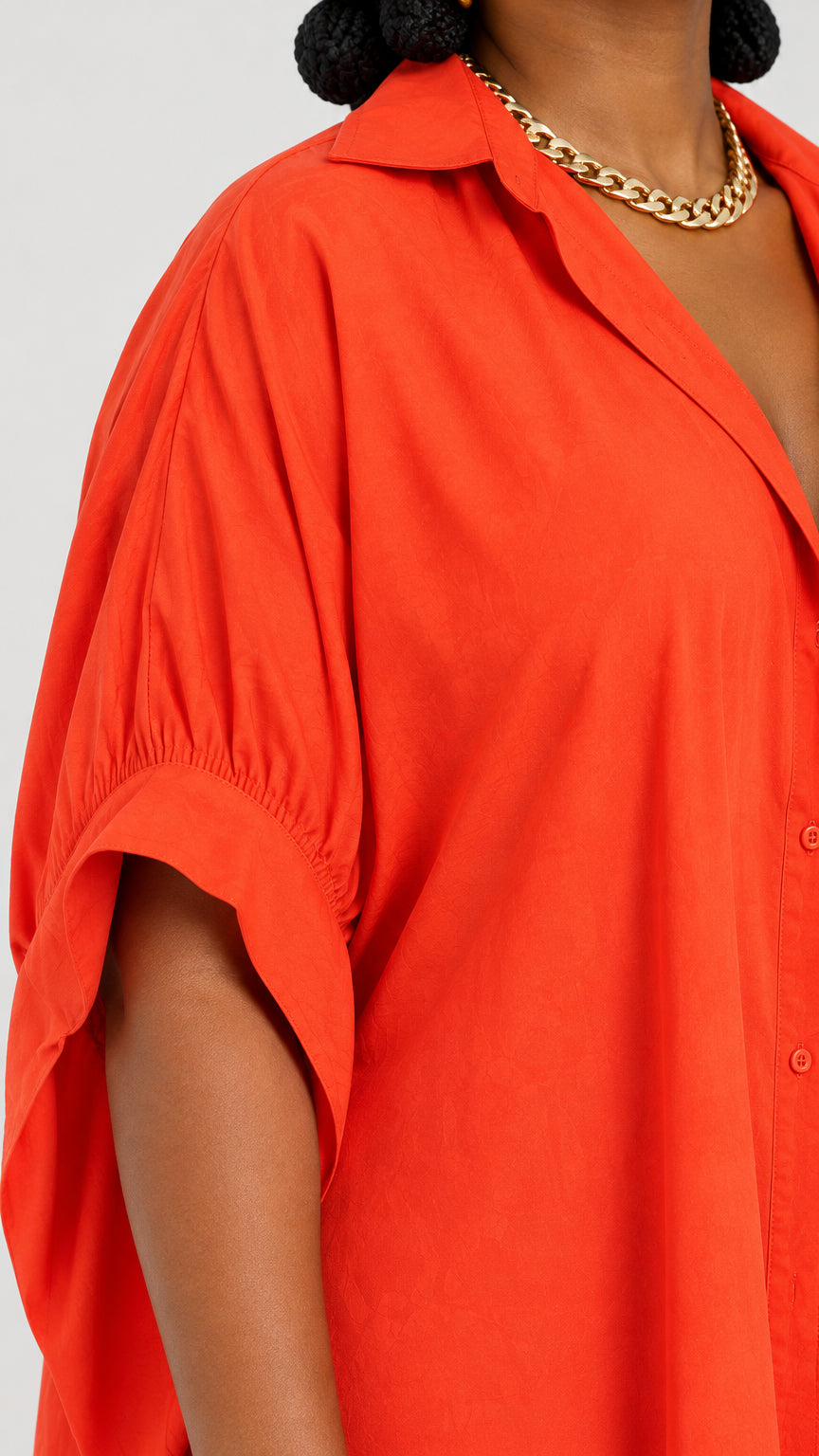 Close-up detail of lapel collar and ruched sleeve on orange shirt dress