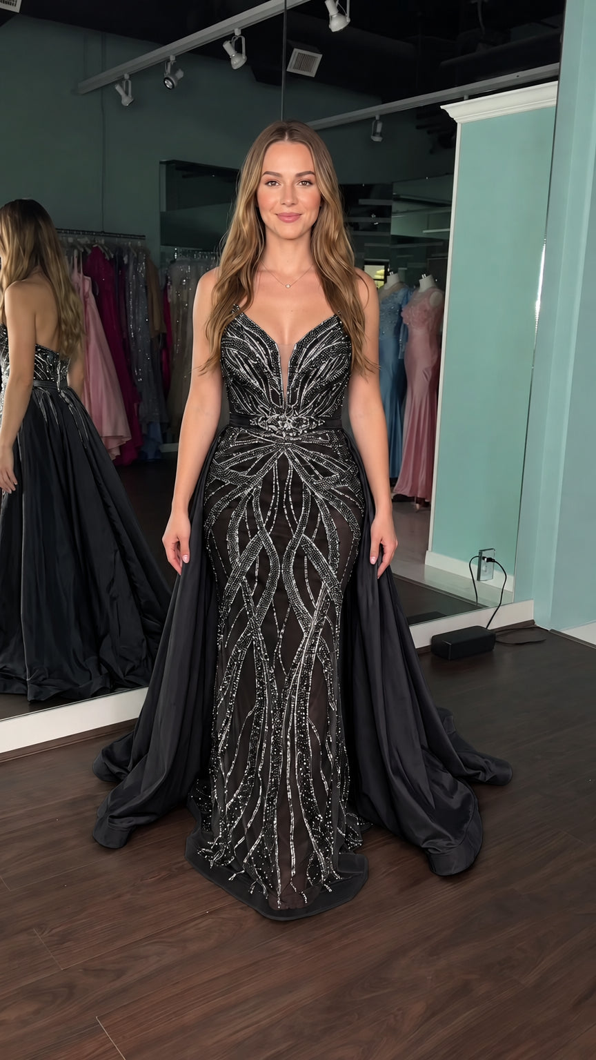 Model wearing black sequined plunge evening gown with voluminous matching overskirt