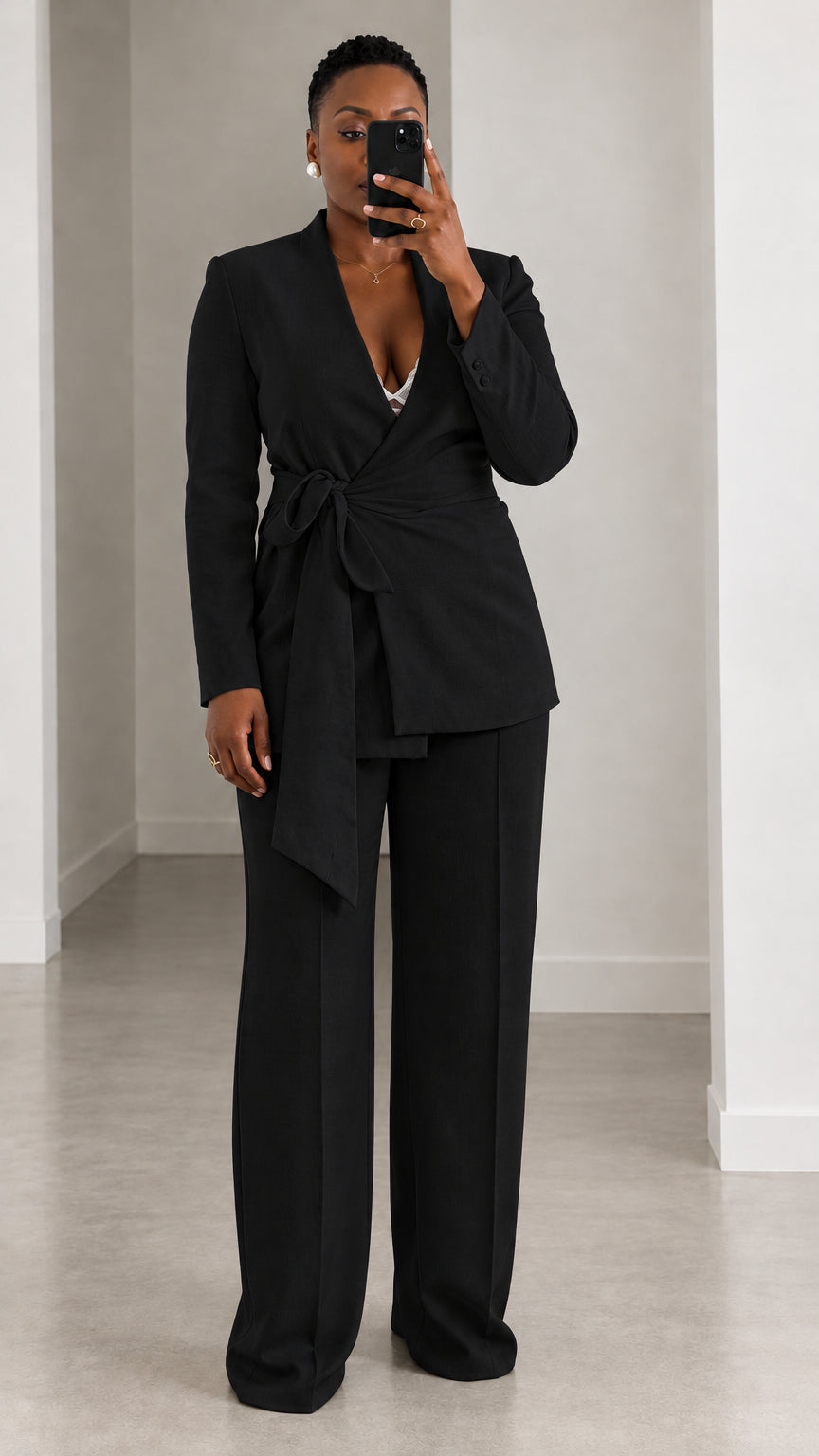 Model wearing all-black tie-waist wrap blazer and matching wide leg suit trousers
