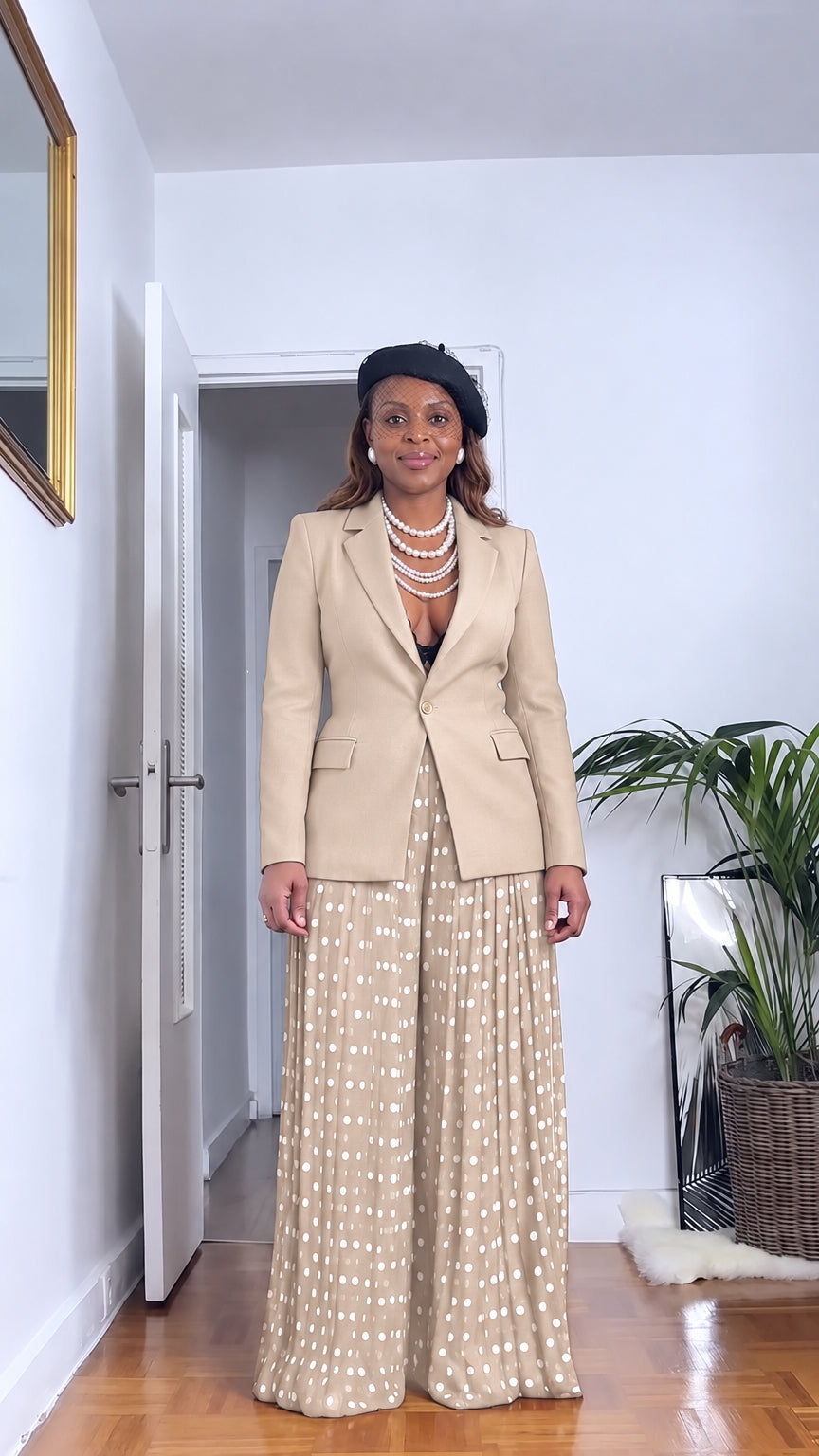 Front full view of woman wearing beige tailored blazer and beige polka dot pleated wide leg pants